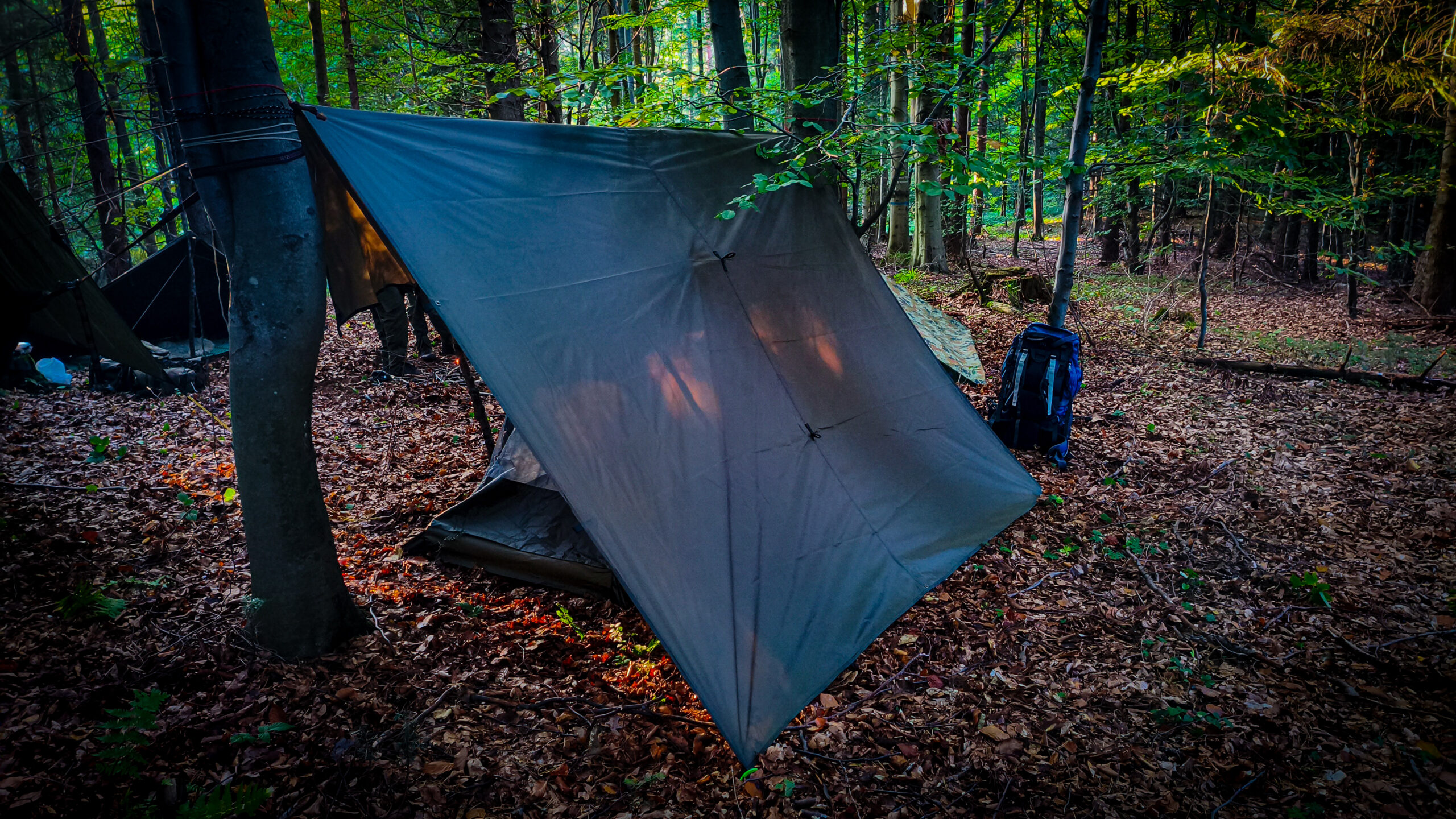 Tarp 3x3 metra rozłożony nad miejscem biwakowym w lesie