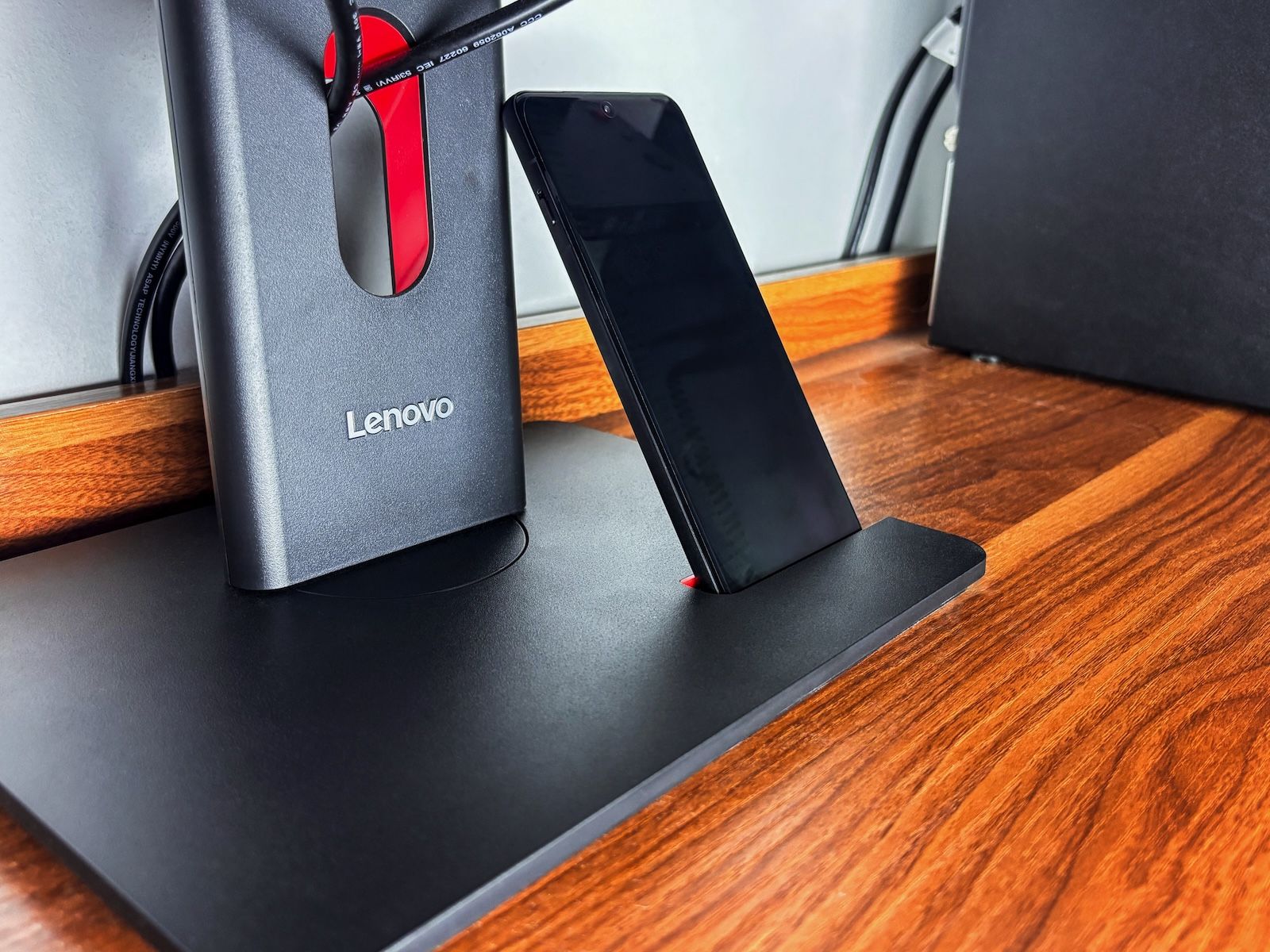 Praktyczne zastosowanie uchwytu w podstawie monitora Lenovo T24-40, w którym umieszczony jest smartfon