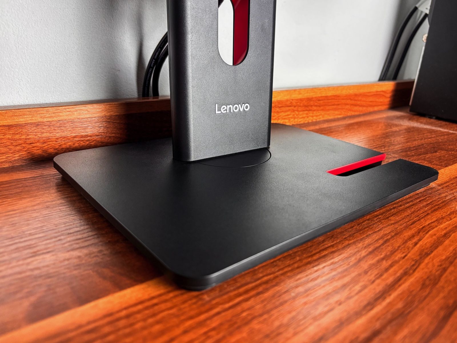 Zbliżenie na ciężką, stabilną podstawę monitora Lenovo T24-40 z czerwonym wycięciem na smartfona