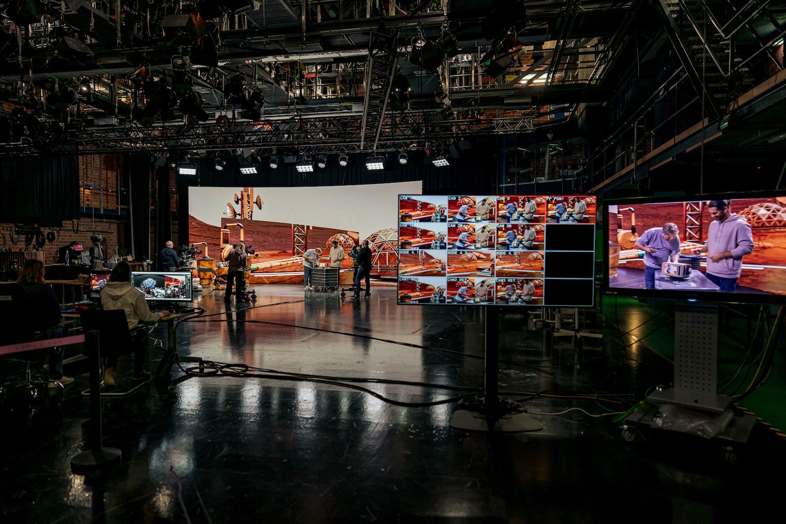 Realizacja wirtualnej produkcji w studiu SWR. Ekipa techniczna i aktorzy przed ekranem Sony VERONA wyświetlającym cyfrową scenografię