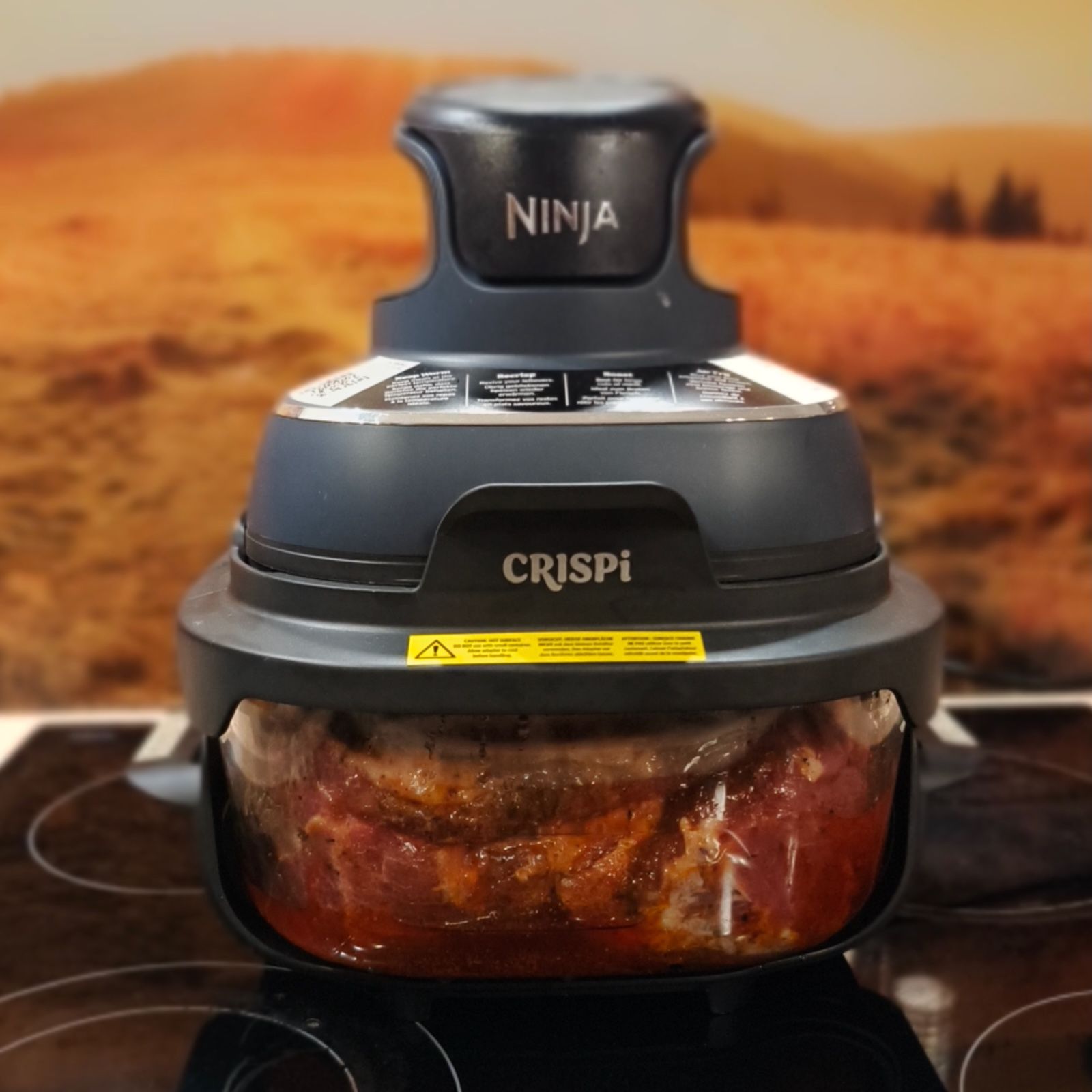 Duży kawałek mięsa pieczony wewnątrz szklanej komory frytownicy Ninja Crispi widoczny przez przezroczyste ścianki