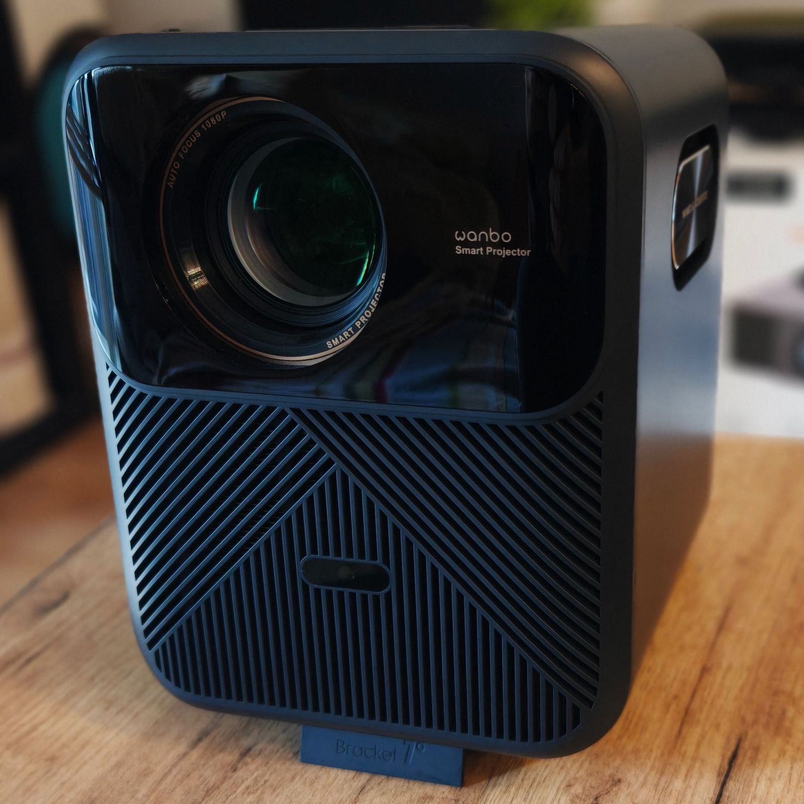 Front projektora Wanbo Mozart 1 Pro na podstawce z widocznym obiektywem i logo