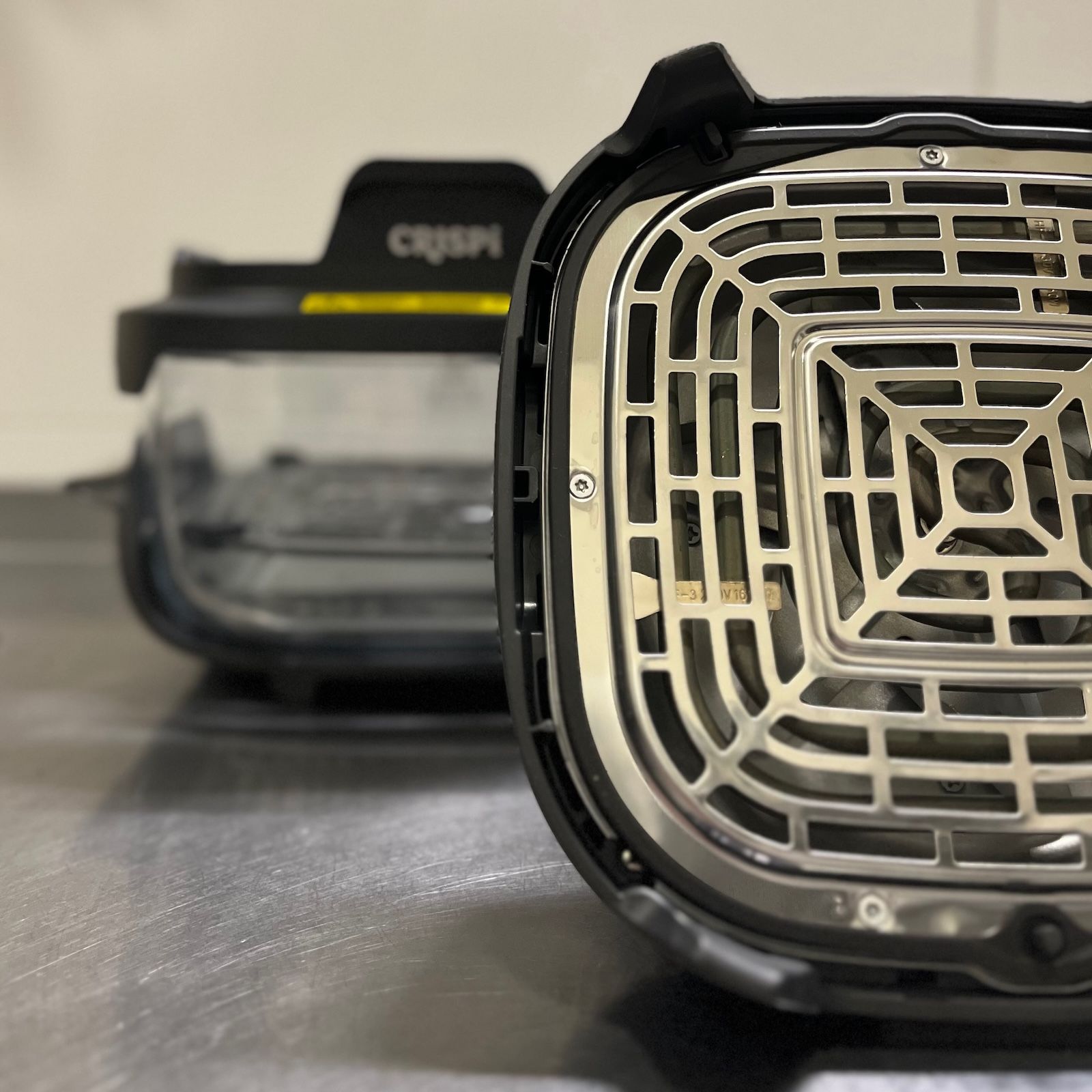 Odsłonięta metalowa kratka osłaniająca grzałkę i wentylator na spodzie głowicy grzewczej urządzenia Ninja Crispi