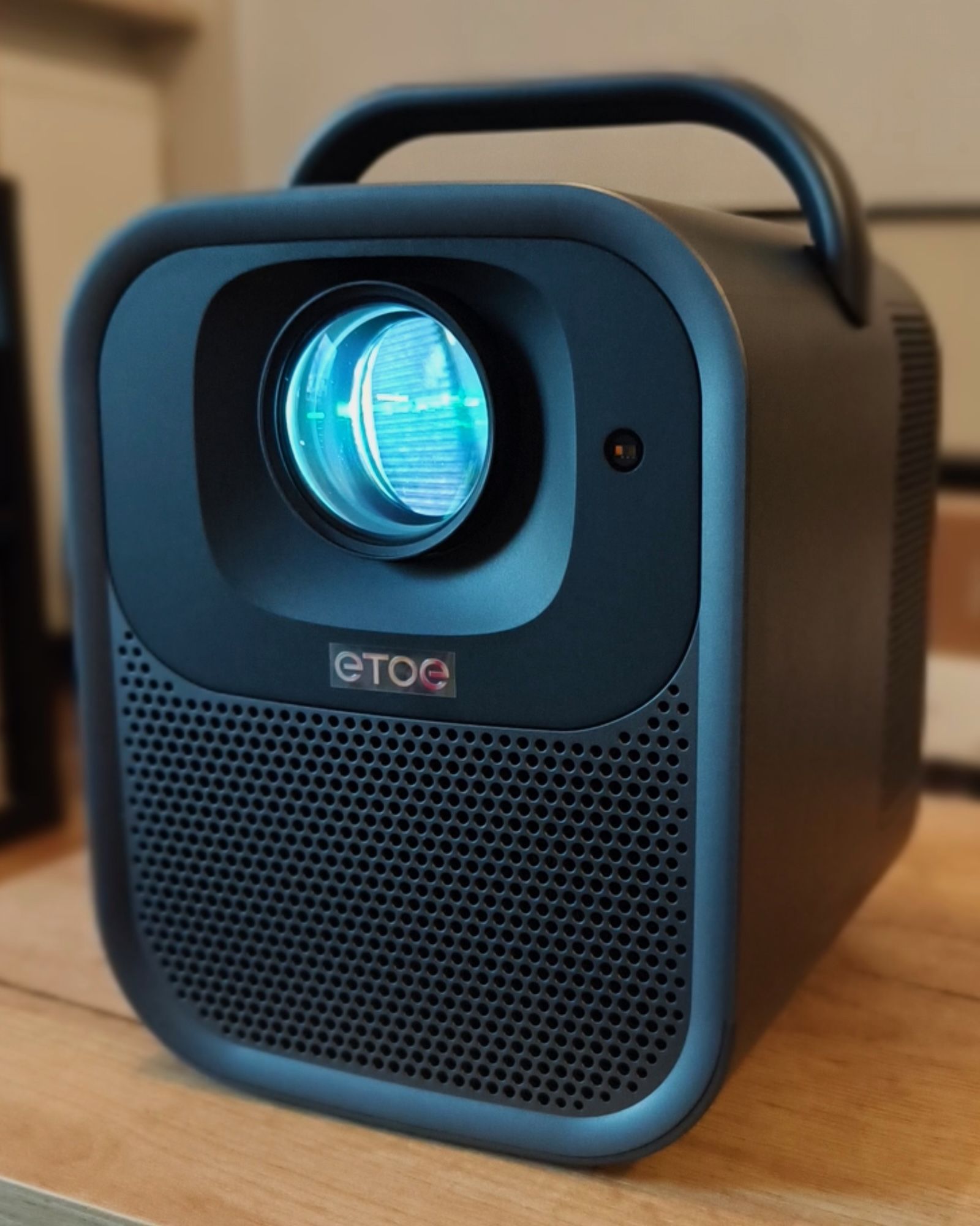 Projektor ETOE Seal Pro widziany pod kątem, pokazujący przedni panel z dużym obiektywem, logo producenta, maskownicę głośników oraz zintegrowany górny uchwyt
