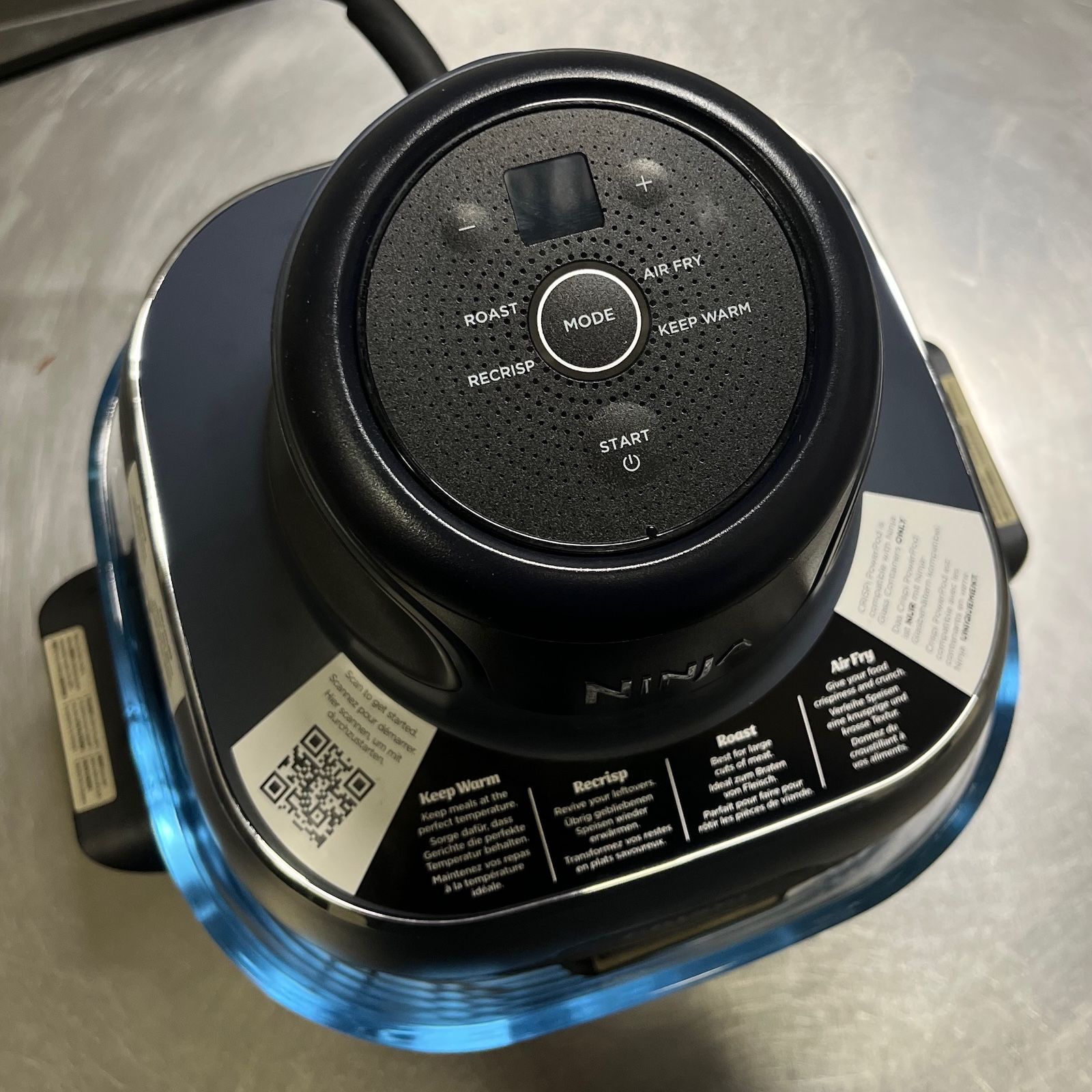 Widok z góry na okrągły panel sterowania urządzenia Ninja Crispi z naklejkami informacyjnymi