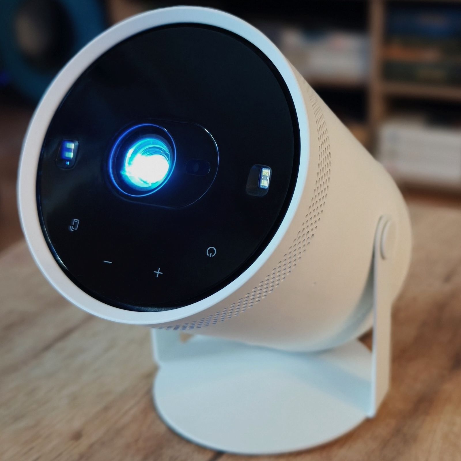 Włączony projektor Samsung The Freestyle Gen 2. Z obiektywu na czarnym panelu przednim emitowane jest jasne światło projekcyjne