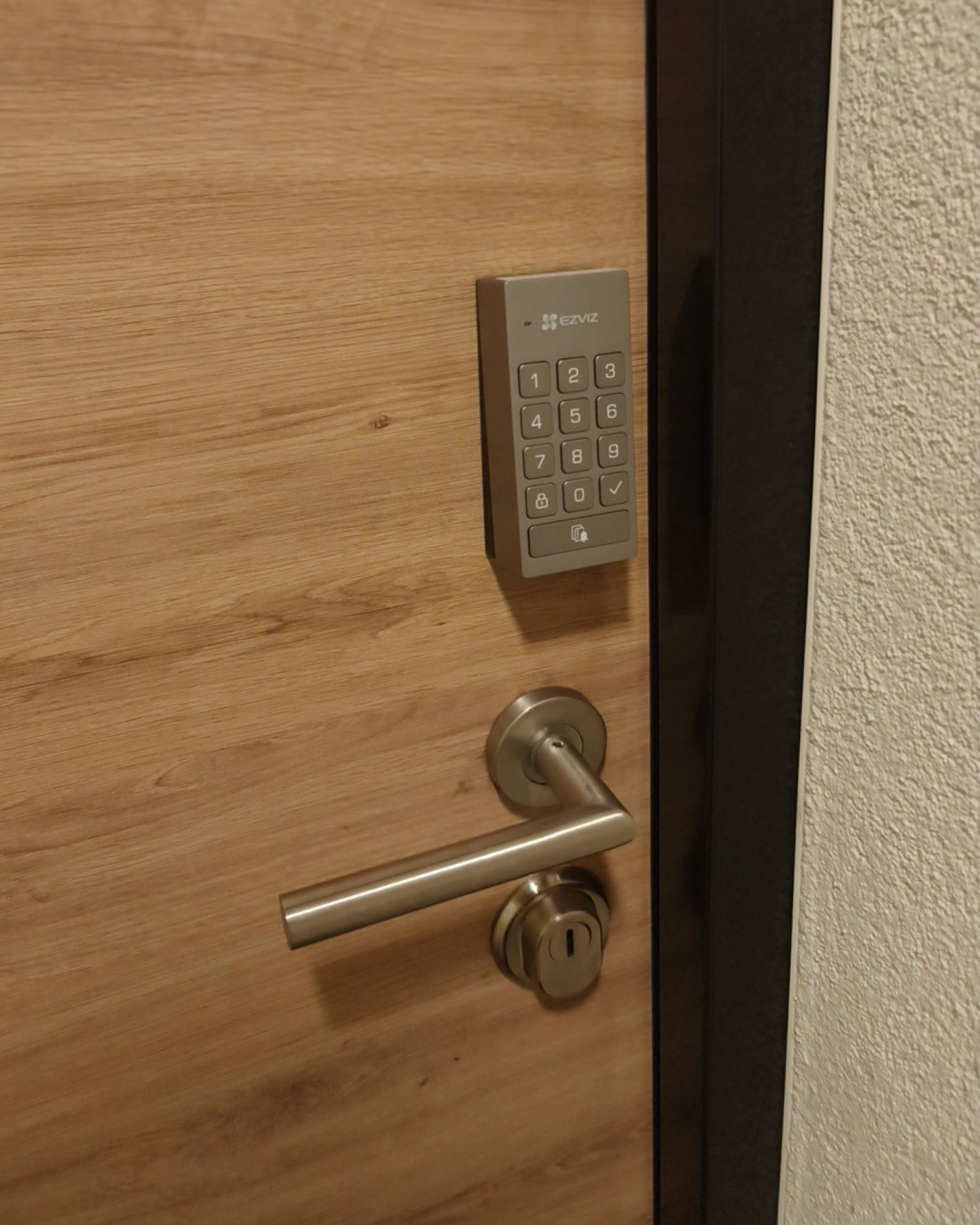 Klawiatura zewnętrzna EZVIZ DL01CP zamontowana na drzwiach nad klamką