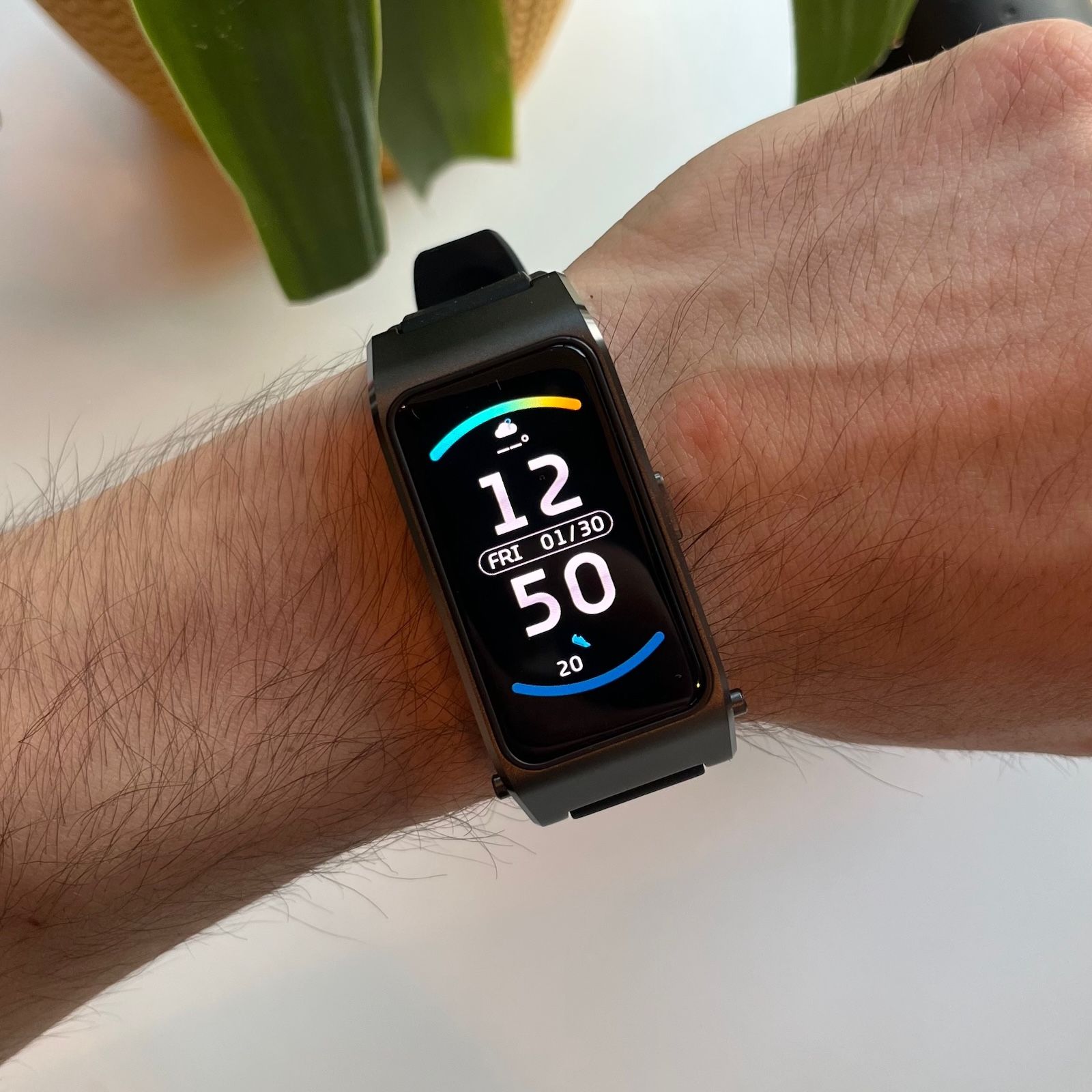 Moduł smartwatcha wpięty w gumowy pasek i założony na nadgarstku, włączony ekran