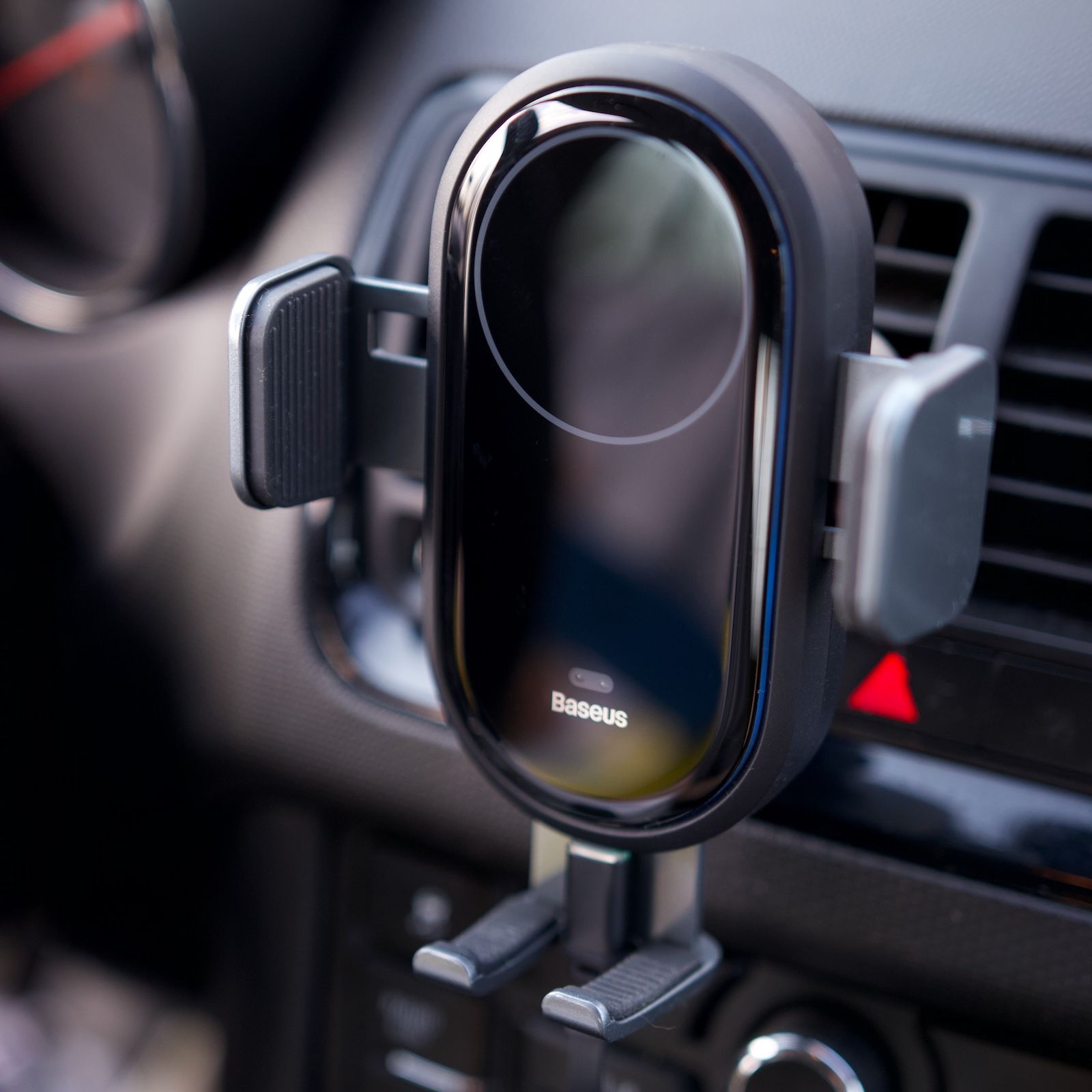 Otwarty uchwyt elektryczny Baseus LightChaser gotowy na odłożenie telefonu, zamontowany na kratce nawiewu