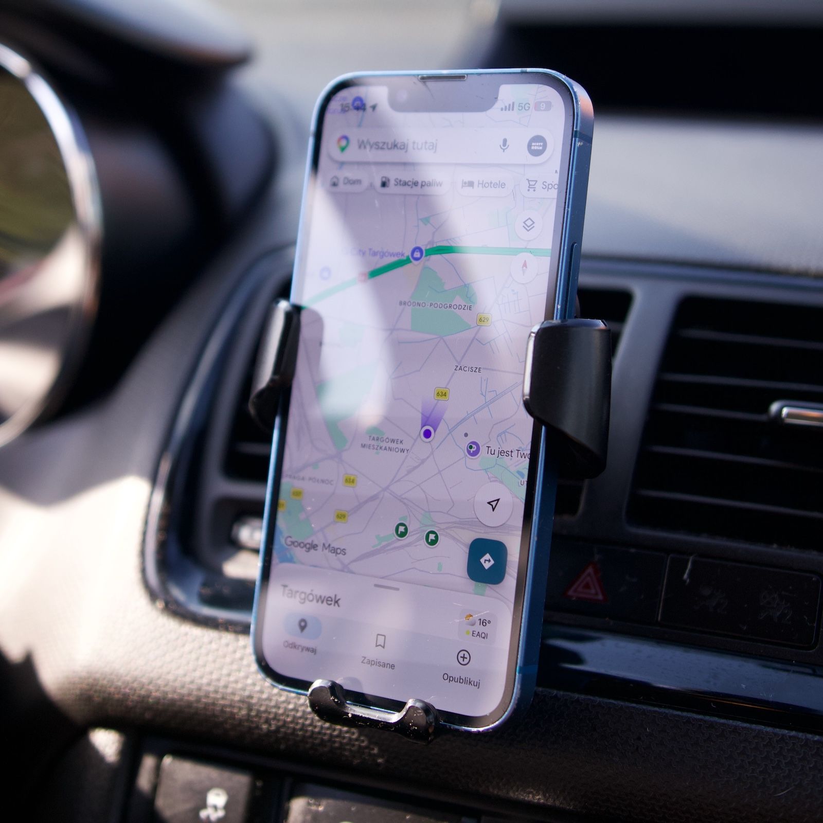 Smartfon z włączoną nawigacją w zaciśniętym grawitacyjnym uchwycie Baseus Gravity na kratce nawiewu