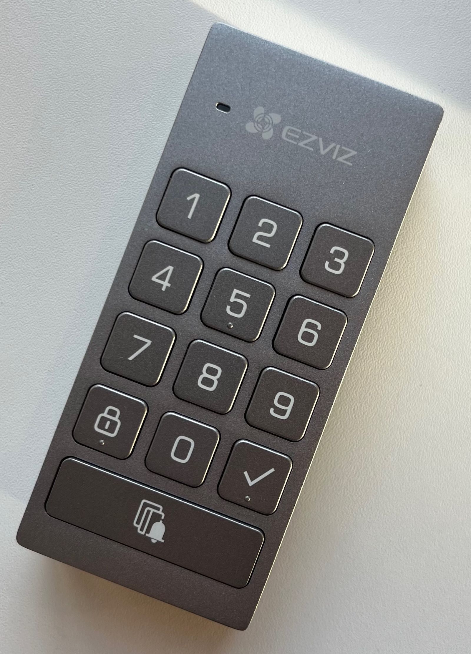 Szara klawiatura zewnętrzna EZVIZ DL01CP z widocznymi przyciskami numerycznymi i dzwonkiem