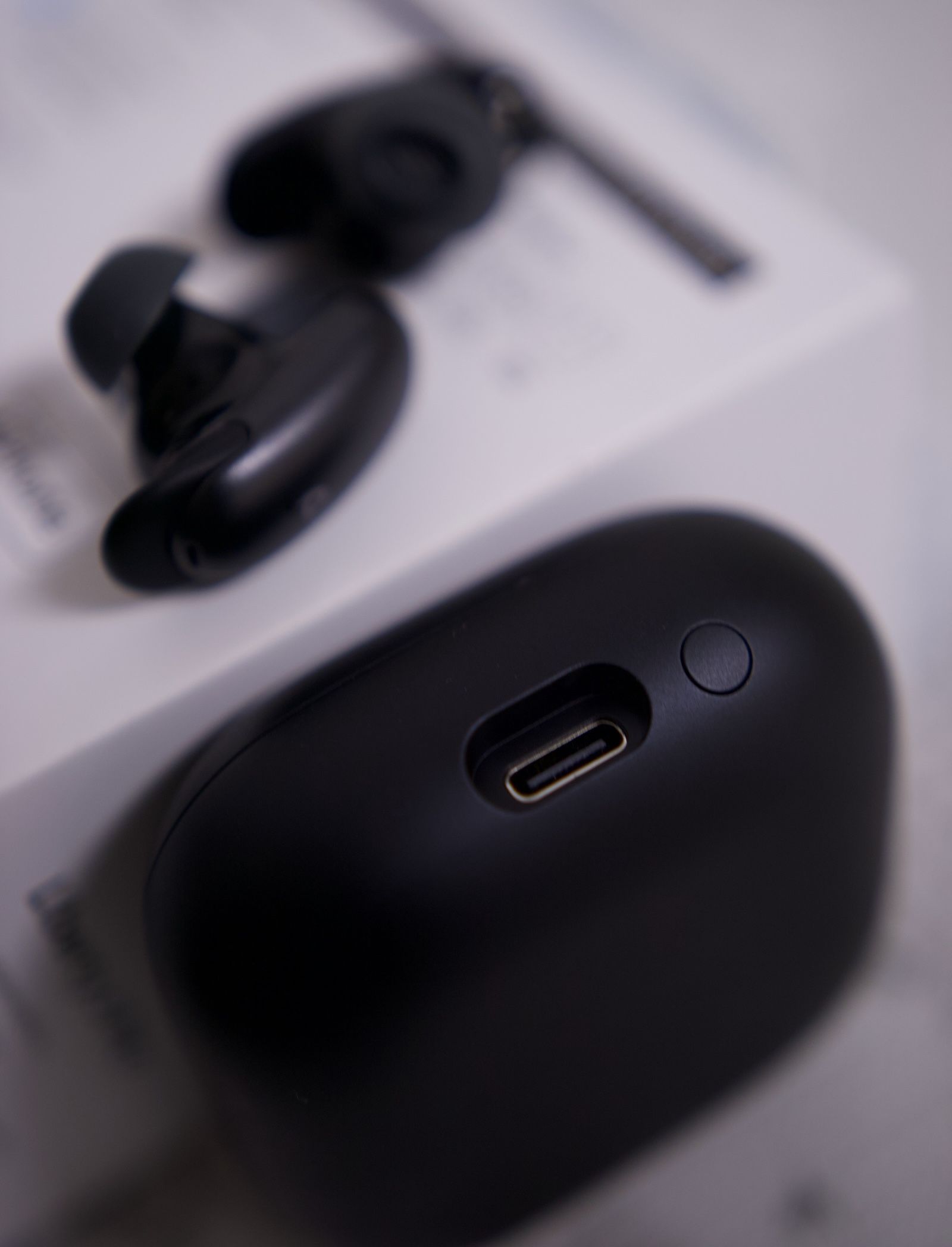 Widok na port USB-C i przycisk parowania umieszczone na bocznej ściance czarnego etui ładującego Soundcore Liberty 5 Pro