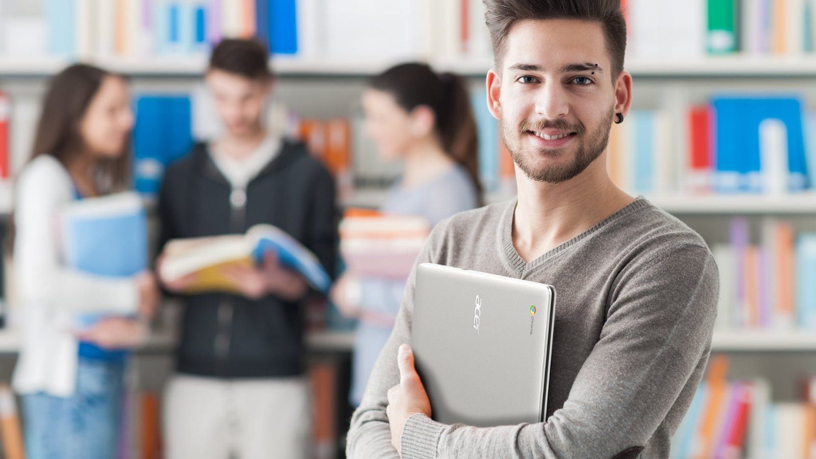 Uśmiechnięty student z Acer Chromebookiem w bibliotece.