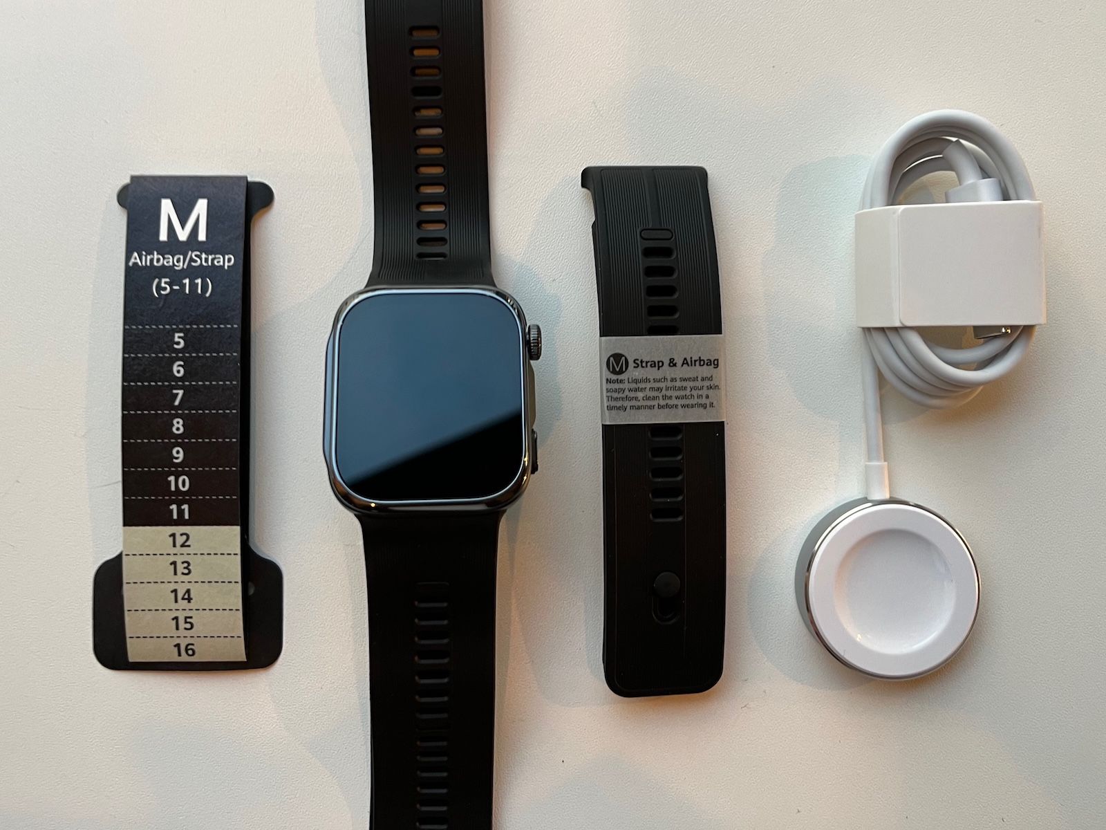 HUAWEI WATCH D3 zegarek obok ładowarki, dodatkowego paska z poduszką oraz miarki rozmiaru M